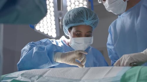 Diverse female surgeons operating on patient in operating theatre, slow motion