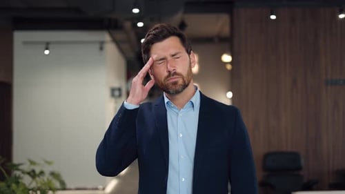 Tired Caucasian Man Massaging Temples Because of Headache in Business Center