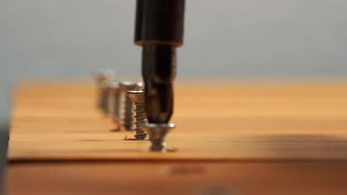 Driving Silver Screws Into Light Brown Surface
