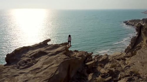 a man stand alone on sea side high rock cliff beach in sunset time a wide view of ocean harbor coast