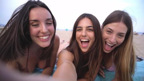 Three Women Friends Lying on Beach Laughing