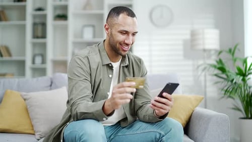 Young Adult Shopping Online With Phone and Card