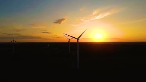 Wind Turbines Silhouetted Against Golden Sunset