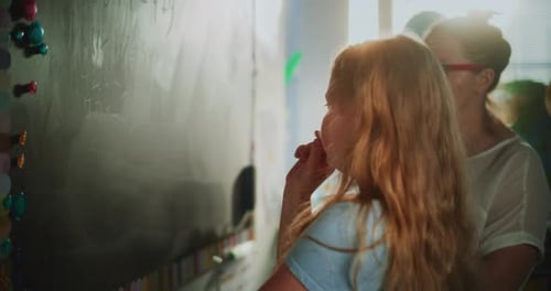 Elementary School Girl Solving Mathematical Problems on the Chalkboard with Female Teacher