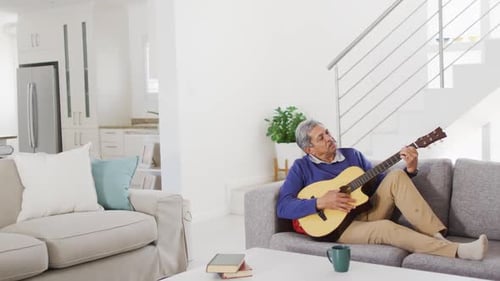 Senior Man Plays Guitar on Couch at Home