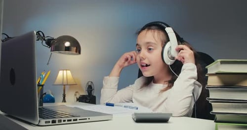 Girl Studies with Laptop and Headphones at Desk