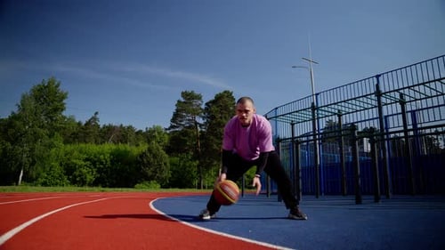 Ralenti : athlète jouant au basket en dribble sur un terrain extérieur