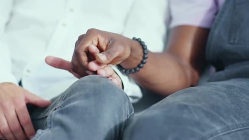 A Man and a Woman are Gently Holding Hands While Sitting on Their Couch