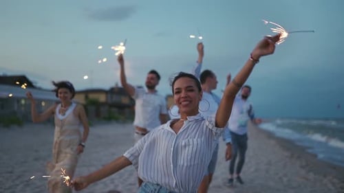 Friends Celebrate Birthday with Sparklers on Beach at Night