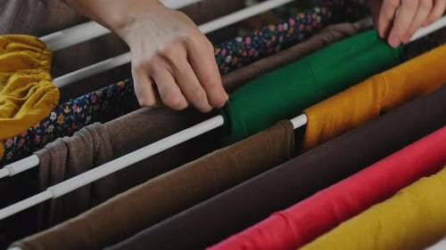 Hands Arranging Clothes on Drying Rack Indoors