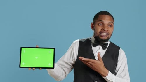 Doorkeeper Bellboy Poses with Green Screen on Tablet at the Hotel Reception
