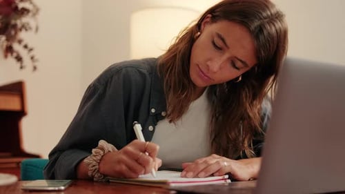 Young Woman Working at a Laptop and Writing