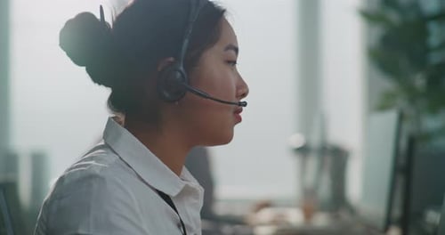 Asian Technical Support Specialist Talking with Customer Using Headset