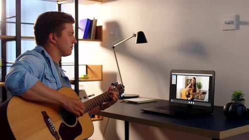 Man taking guitar lesson on a computer at home