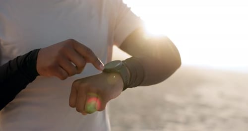 Person Using Smartwatch on a Beach at Sunrise