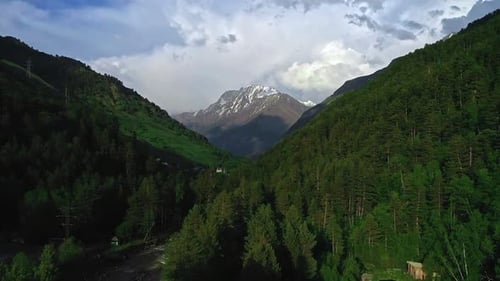Majestic Mountain Range with Forest River and Cloudy Sky