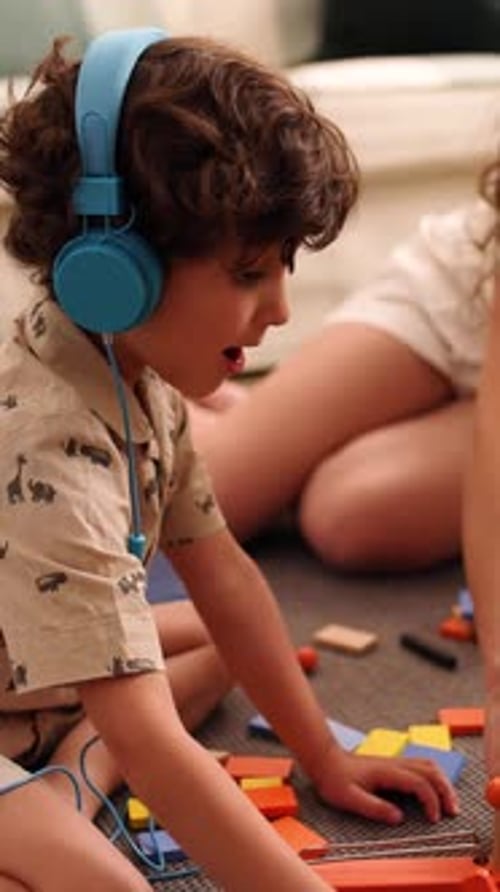 Boy with Headphones Playing with Blocks with Friend