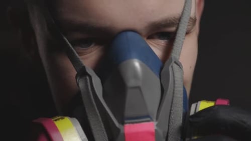 A Man Wear A Colorful Respirator Through Its Headband And Fits Half Of His Face. -close up shot