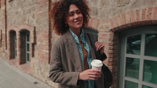 Woman Walking with Coffee in Urban Setting