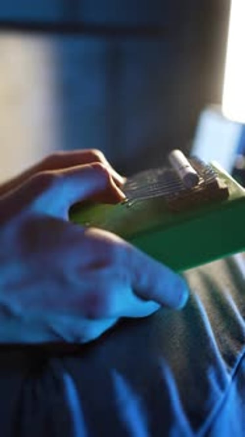 Skilled Female Performer Gently Manipulating Green Kalimba Producing Delicate Acoustic Melodies
