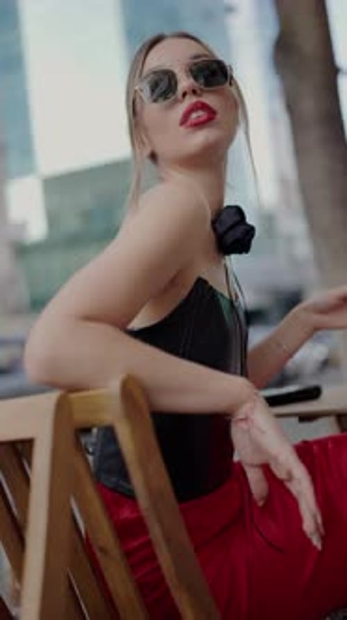 Fashionable Woman Sitting Outdoors in the City Wearing Stylish Sunglasses