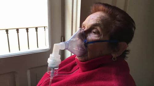 Femme âgée recevant un traitement des voies respiratoires à domicile au Ralenti