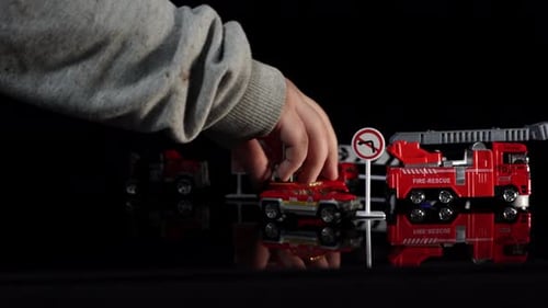 Child's Hand Playing with Toy Firetrucks
