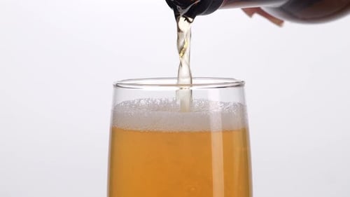 Close Up Slow Motion Of Hand Holding A Glass Bottle Pouring Beer Into A Glass On White Background