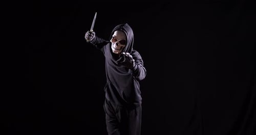 Hooded Figure in Skull Mask Threatens with Knife