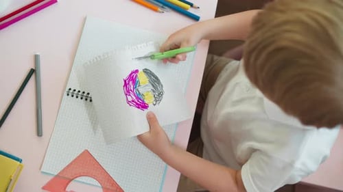 Child Cuts Perforated Edge of Sketchbook Page with Picture