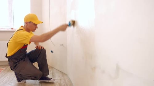 Builder Covers the Wall with Wallpaper Glue