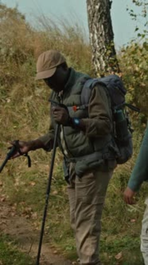 Three Tourists with Backpacks Walking down Path Following One Another