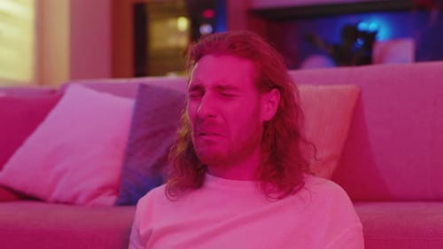 Young Surprised Handsome Caucasian Man Watching TV at Home Getting Scared of Horror Movie Scenes