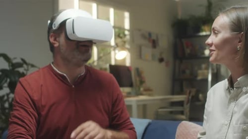 Woman Helping Man Use Virtual Reality Headset