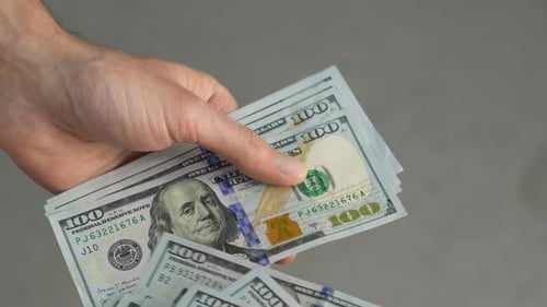 Hand Counts Stack of One Hundred Dollar Bills