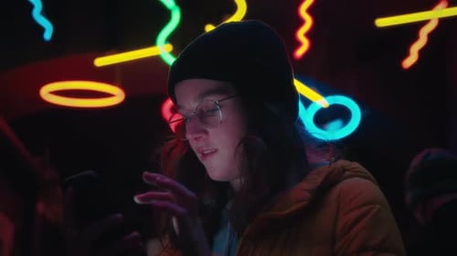Young Woman Uses Phone with Neon Lights