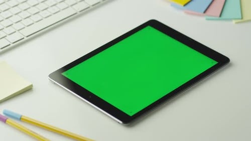 O designer está usando o tablet com tela verde no modo paisagem.