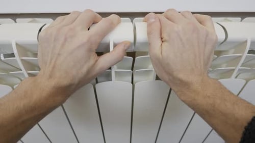 Male Hands Checking Temperature On White Central Heating Radiator In Home