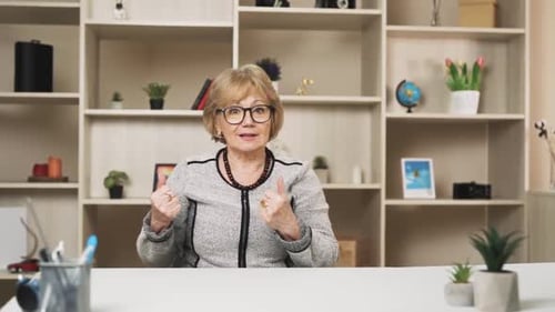 vieille femme charismatique, enseignante, parle en regardant la caméra, en menant une conversation en ligne