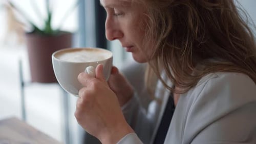 A Woman Sitting in a Cafe Enjoying the Aroma of Her Coffee Cup