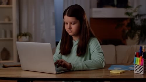 Girl Typing on Laptop at Wooden Desk