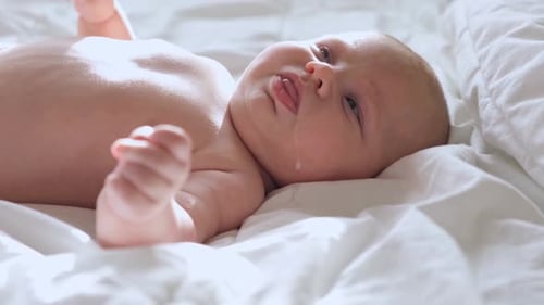 Infant Cries While Lying on White Sheet