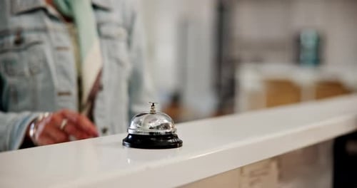 Hotel, reception desk and hand with bell to press, request help and urgent attention for service