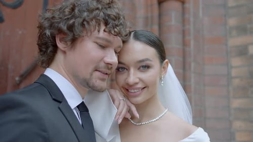 Primer plano de una hermosa pareja de recién casados en acción: recién casados con vestidos de novia en la iglesia felices