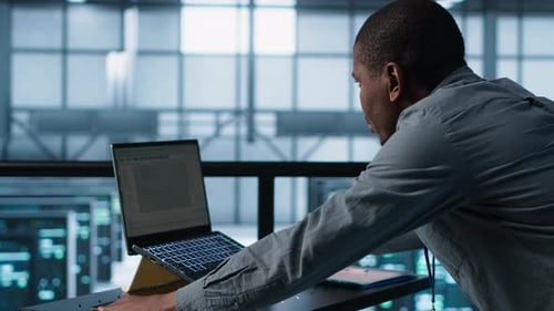 Technician Coding on Laptop in Data Center Managing Server Virtualization