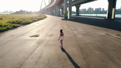 Young Woman in White Shorts Riding a Skateboard Under the