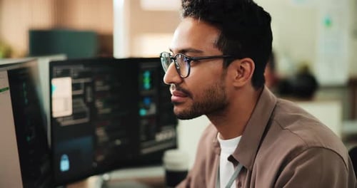 Smiling Man Working with Code on Dual Monitors