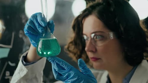 Woman Examining Blue Liquid in Beaker Close Up