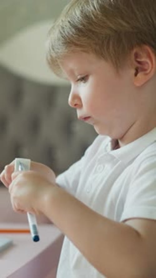 Niño pequeño juega con bolígrafo y goma de borrar sentado en el escritorio