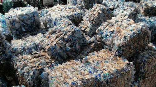 Multiple cubes of compressed plastic garbage at waste recycling factory in open air